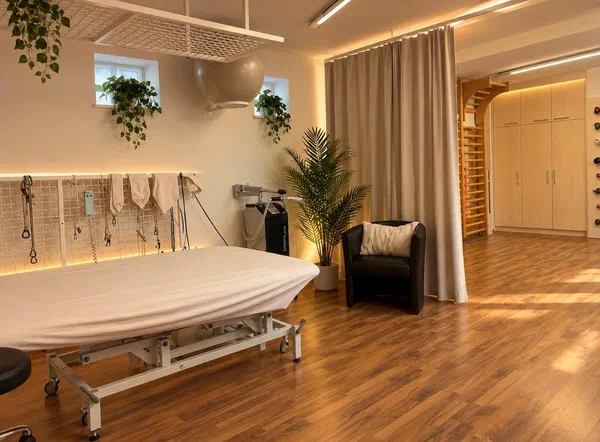 Therapiebereich im Turn- und Trainingssaal mit Behandlungsliege, Sprossenwand und Vorhang